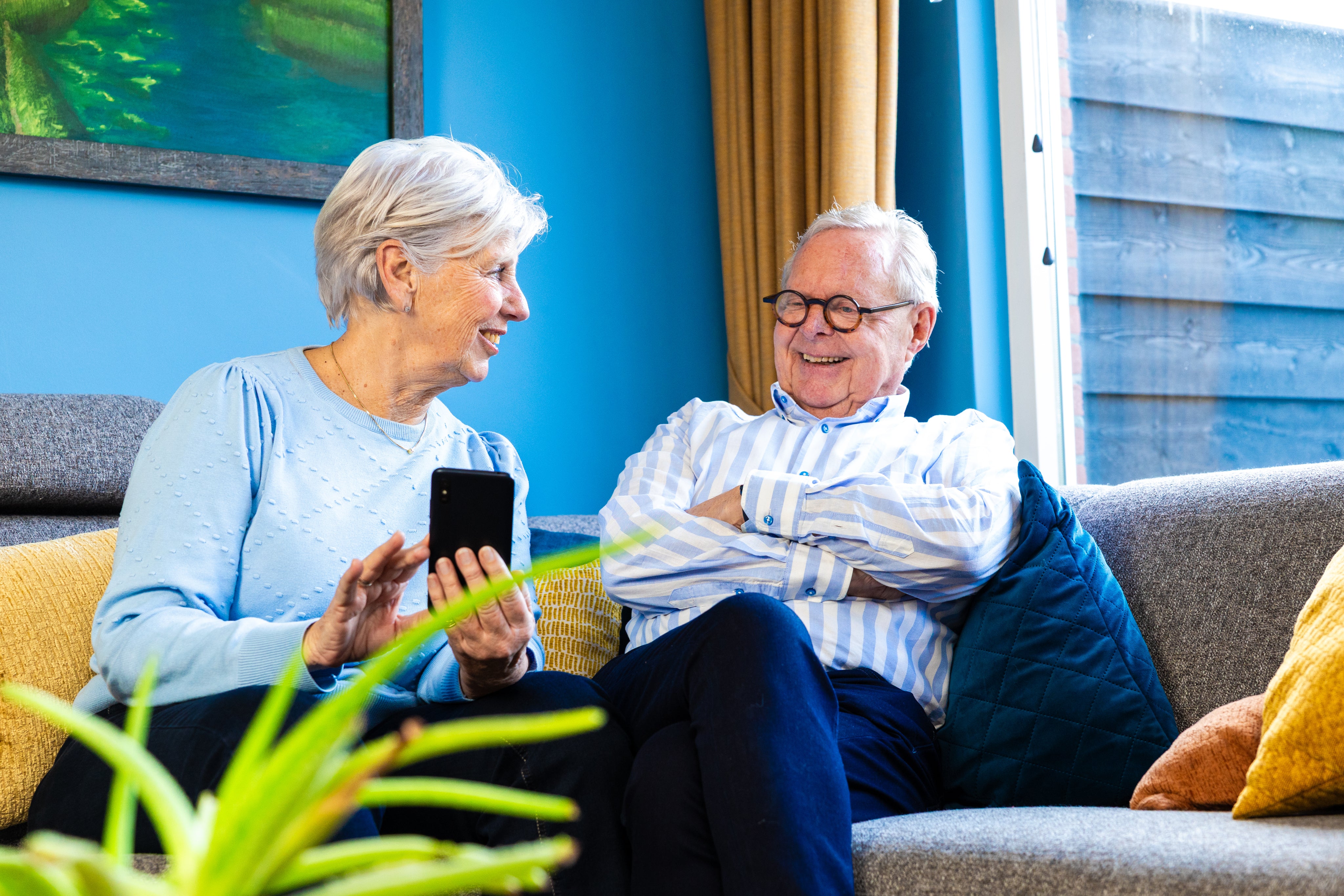 Couple age souriant ensemble en tenant un smartphone